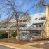 Unique angled roof residential building with large chimneys and leafless trees.