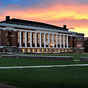 A classic brick building with tall columns at sunset.
