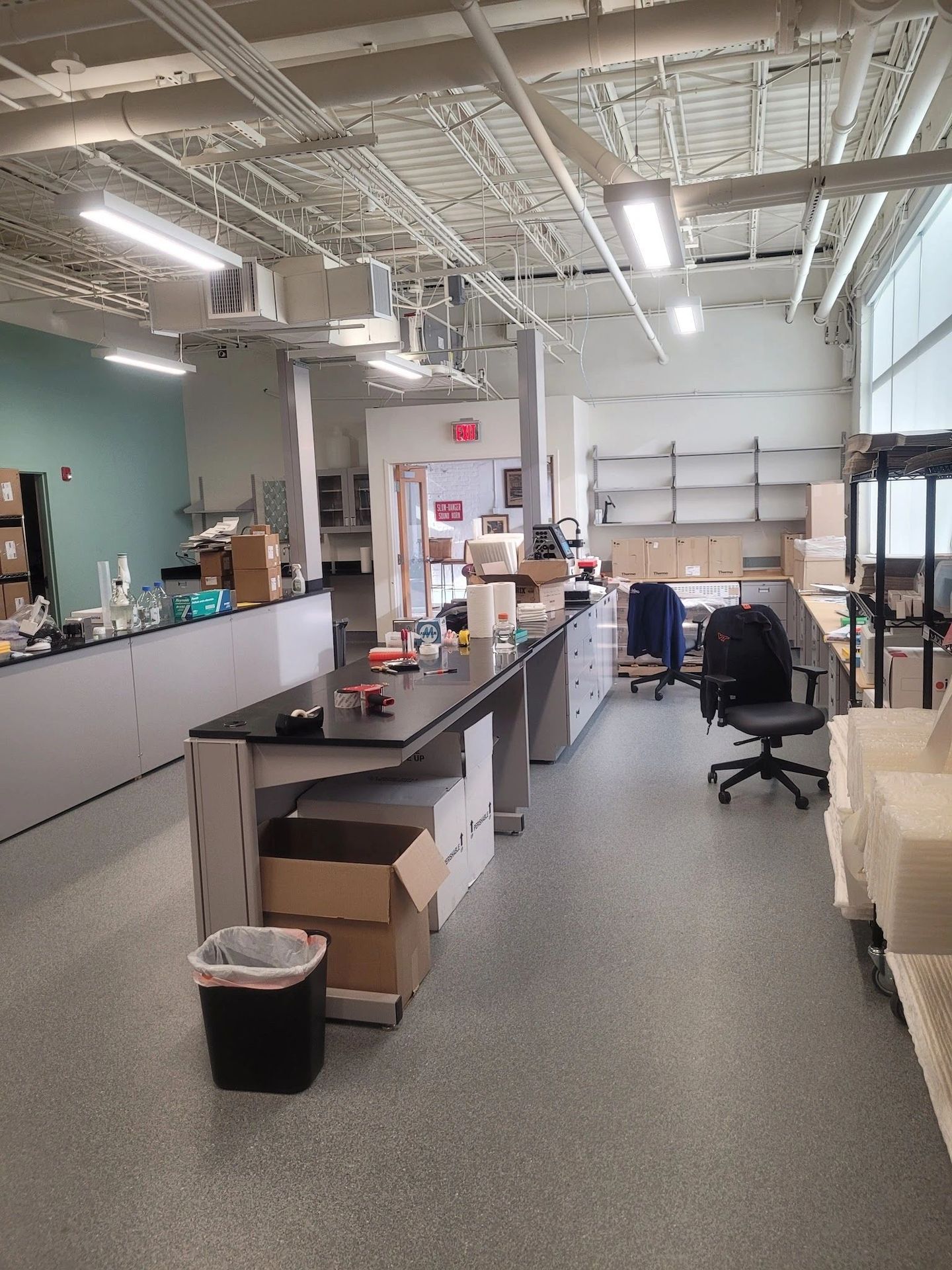A clean, organized laboratory workspace with desks, chairs, and storage boxes.