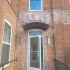 Open glass door on a red brick building with a window above.
