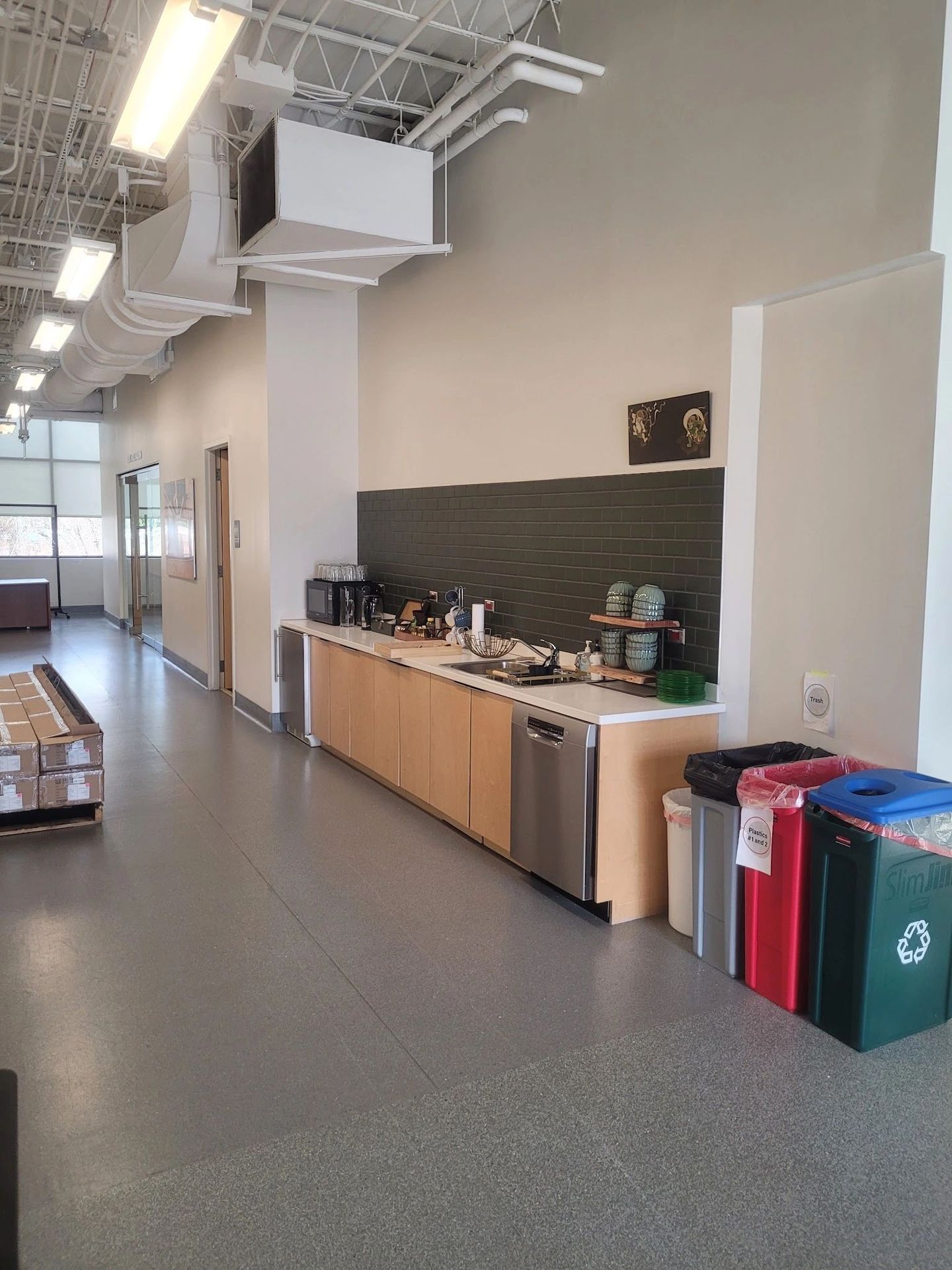 Modern office kitchenette with recycling bins and appliances.
